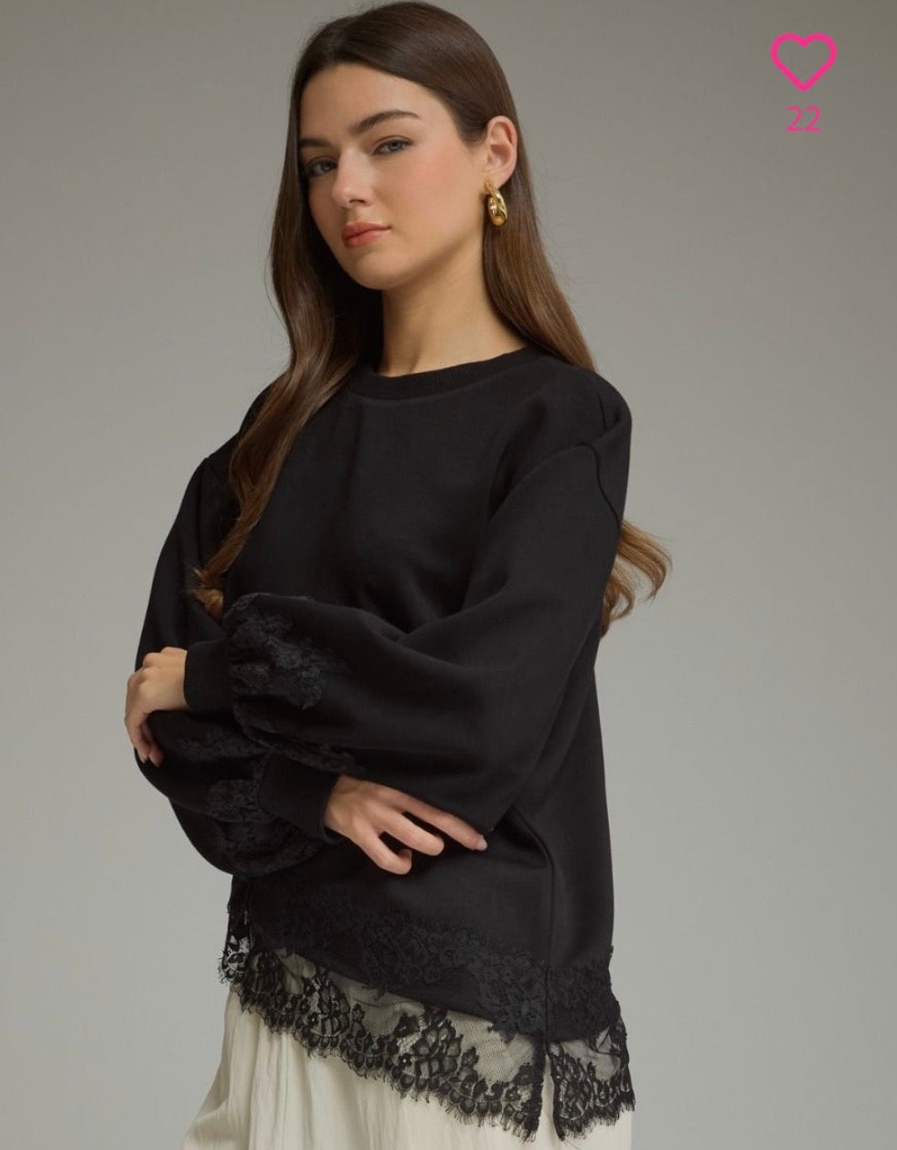 black long-sleeve top with black lace trim at the cuffs and hem, paired with a cream skirt