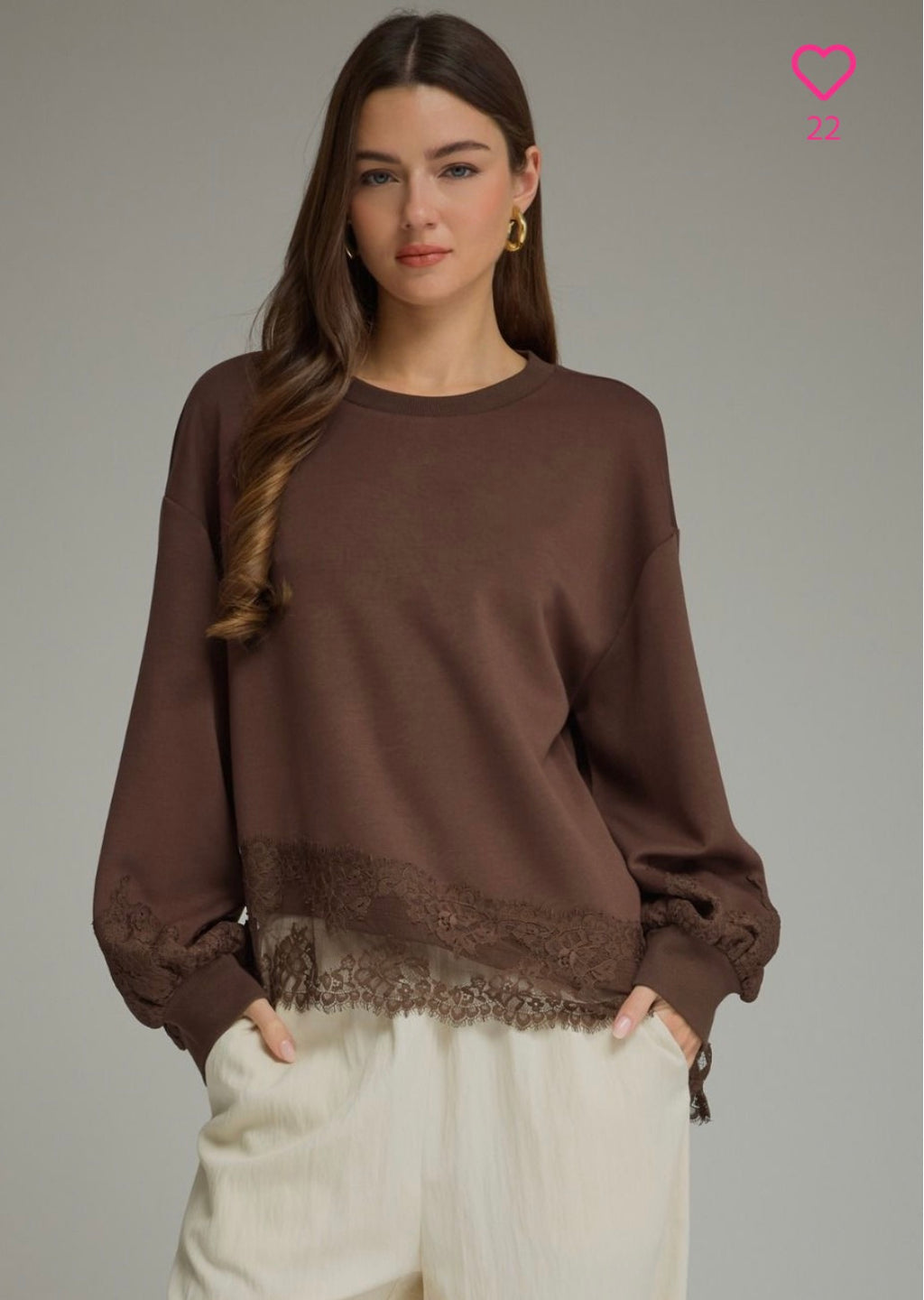 brown crewneck sweatshirt with a lace hem detail, paired with cream-colored pants